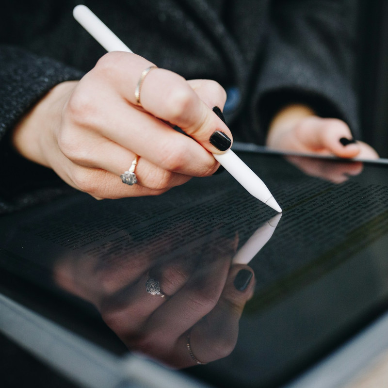 Close-up of a woman's hand signing a document on a tablet with a stylus.